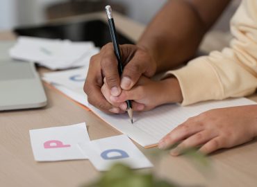 Child practicing handwriting therapy with guided occupational exercises to improve fine motor skills.