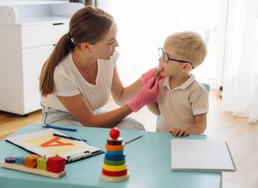 A speech-language pathologist guiding a child through interactive therapy activities to build communication and social skills.